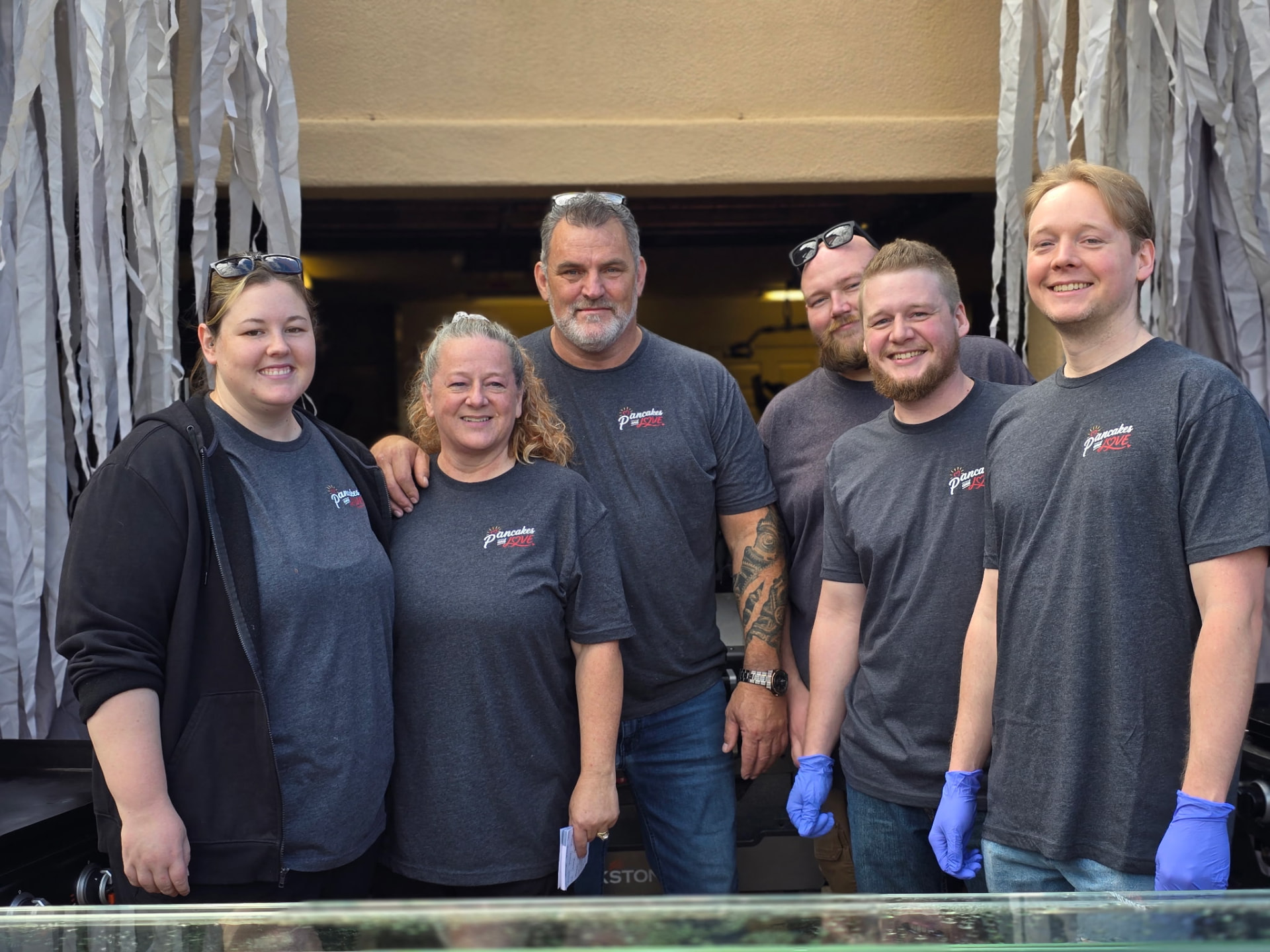 Six Pancakes & Love volunteers gathered together in matching shirts.