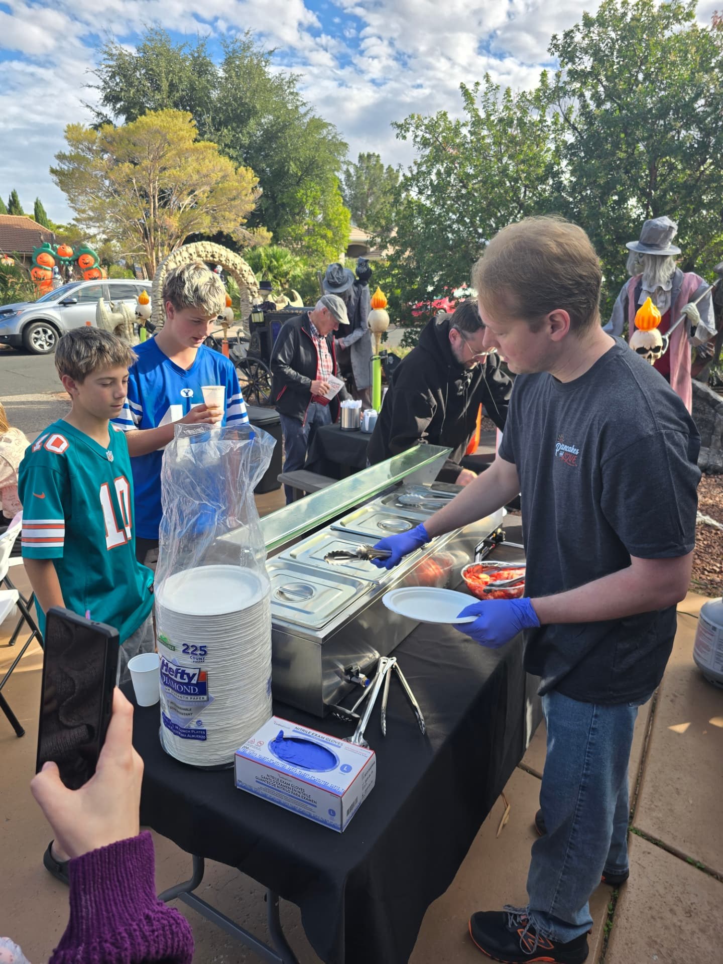 Young volunteers serving breakfast to neighbors at the serving table.