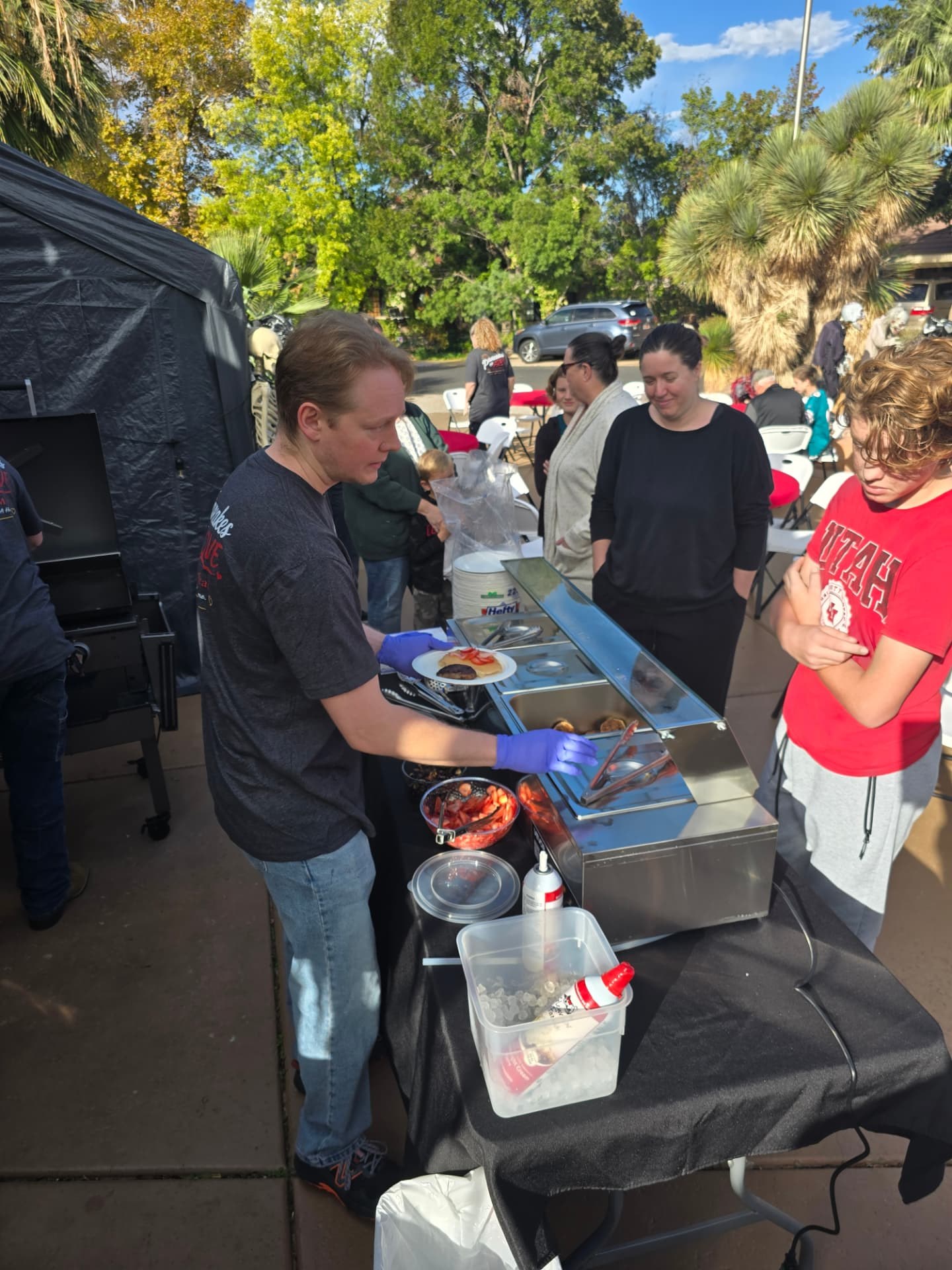 A young volunteer serving plates to neighbors in line.