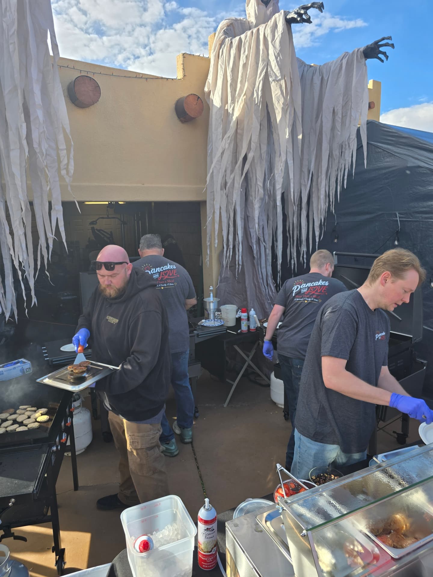 Volunteers cooking and serving beneath the Halloween ghost decorations.