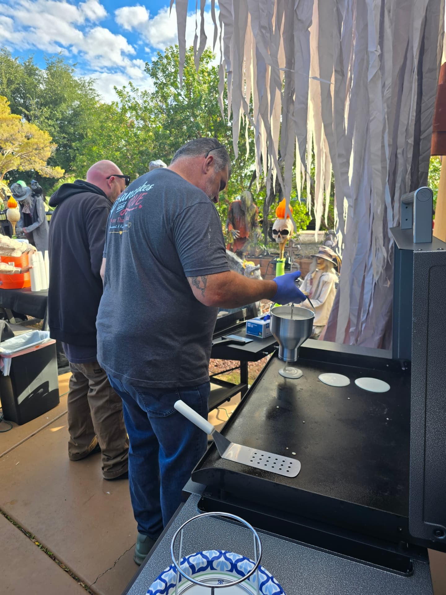 Volunteers flipping pancakes at the griddle among the Halloween decorations.